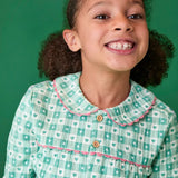 Close up of hild wearing the Frugi magic nights organic cotton hayley traditional pyjamas. Light green and white check style with hearts and stars, pink frill around the collar and across the chest.