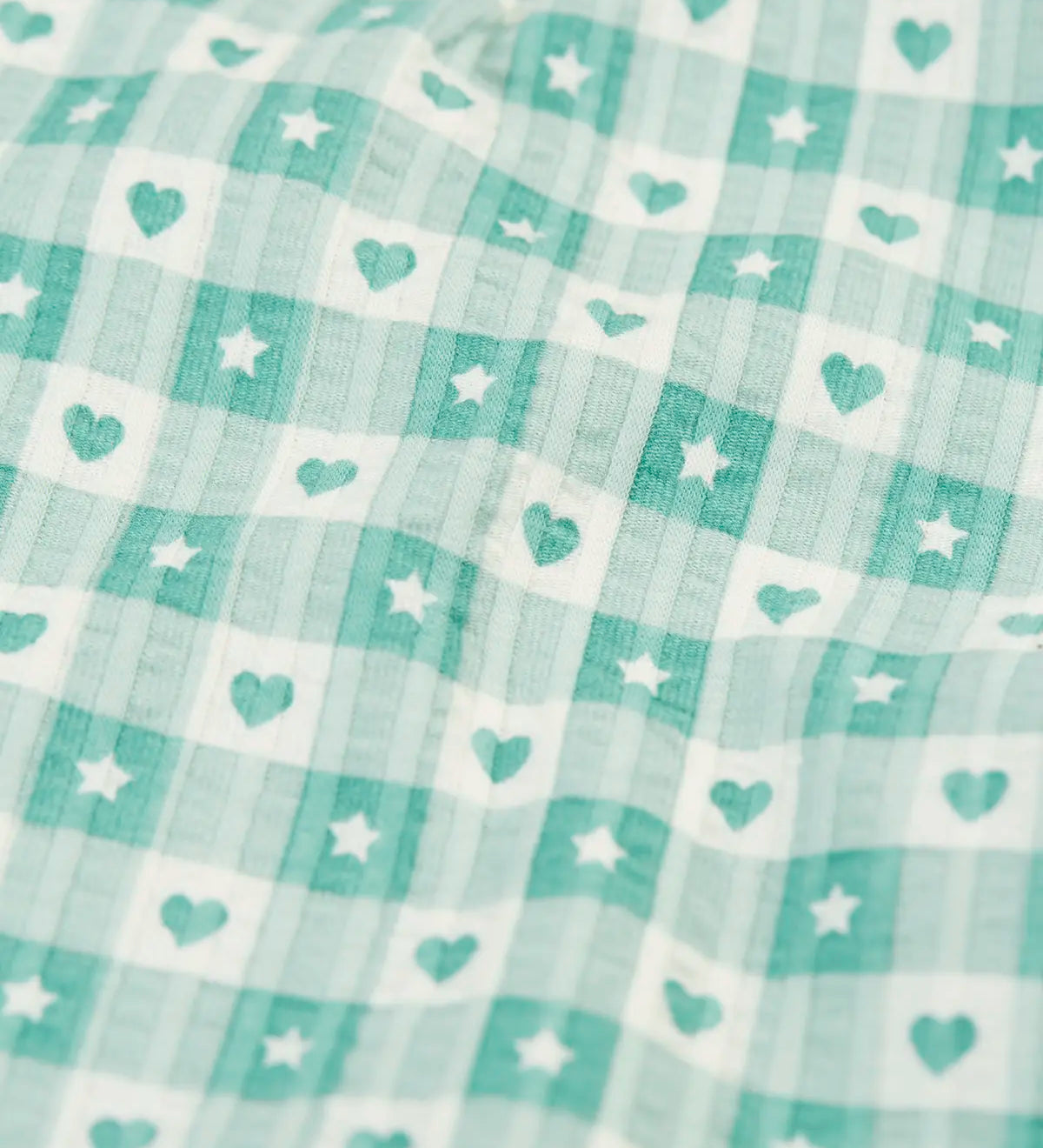Close up of the light green and white check style hearts and stars pattern on the Frugi magic nights organic cotton hayley traditional pyjamas.