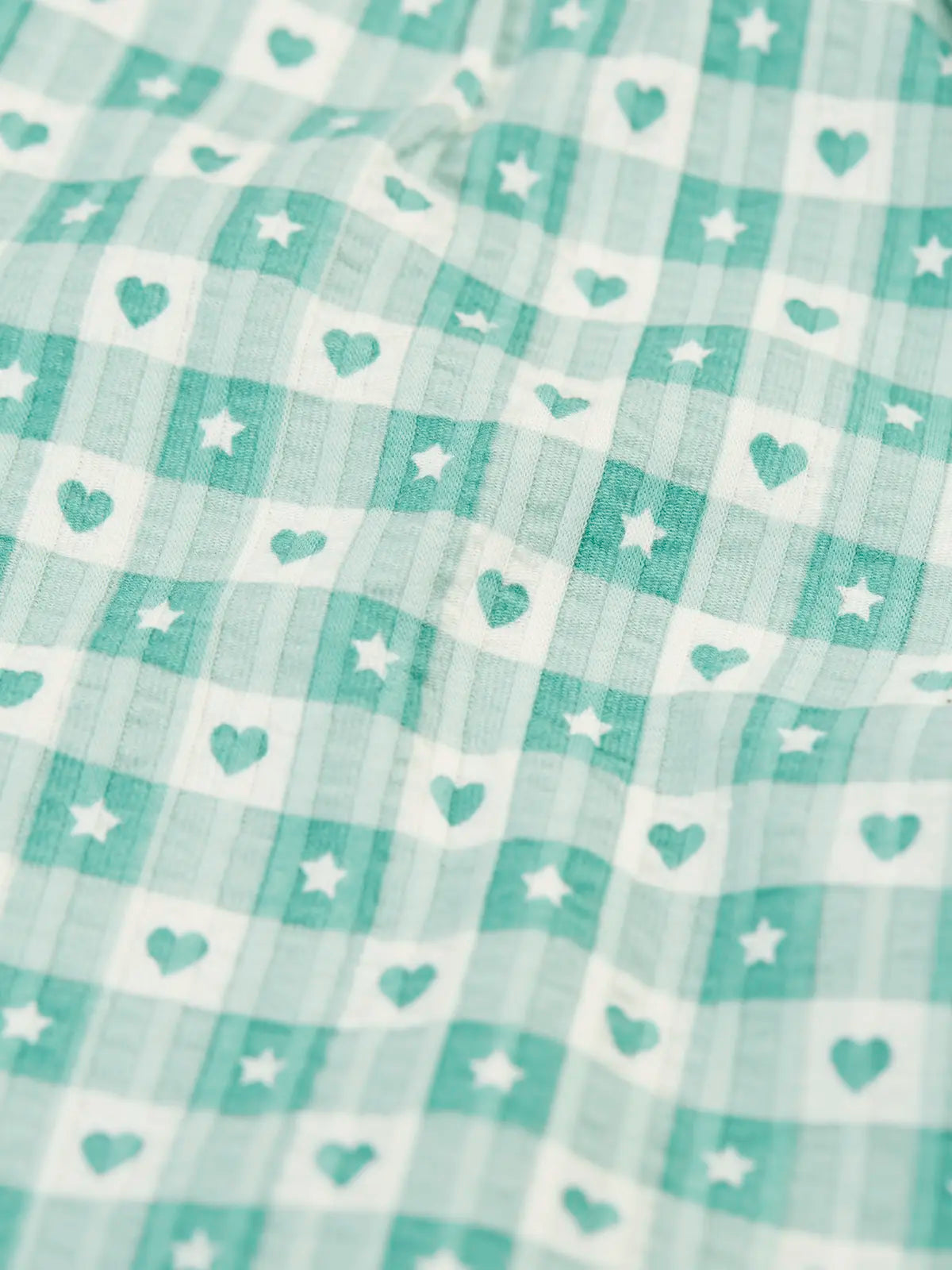 Close up of the light green and white check style hearts and stars pattern on the Frugi magic nights organic cotton hayley traditional pyjamas.