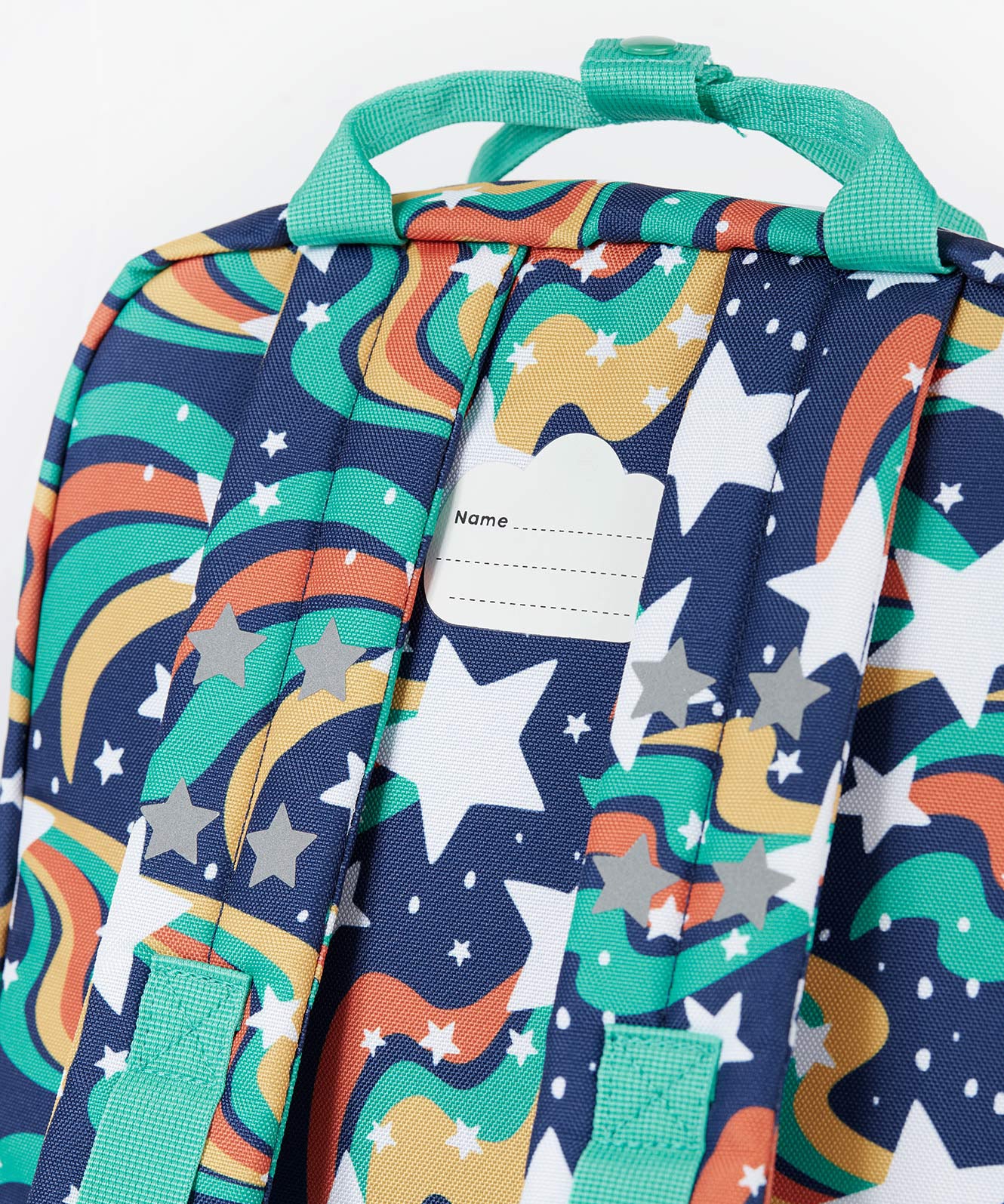 A close up of the back of the Frugi magic stars explorer backpack showing the name tag detail on the top of the bag in between the shoulder straps.