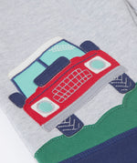 A close up of the red truck applique on the Frugi Malpas Placement Grey Joggers with Trucks.