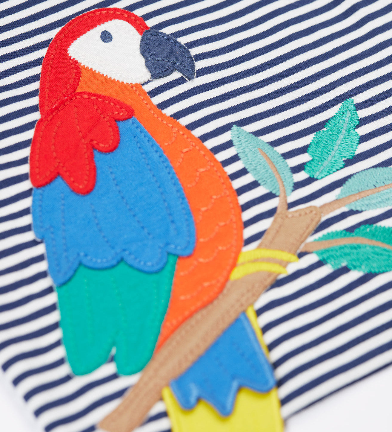 A close up of the Frugi Marco Outfit's t-shirt, in Navy Blue Stripe with an embroidered Parrot.