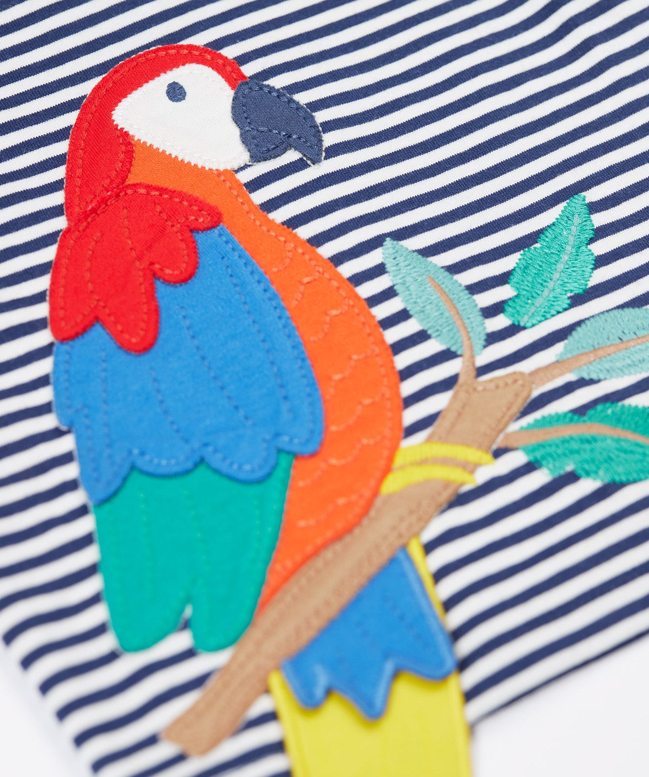 A close up of the Frugi Marco Outfit's t-shirt, in Navy Blue Stripe with an embroidered Parrot.