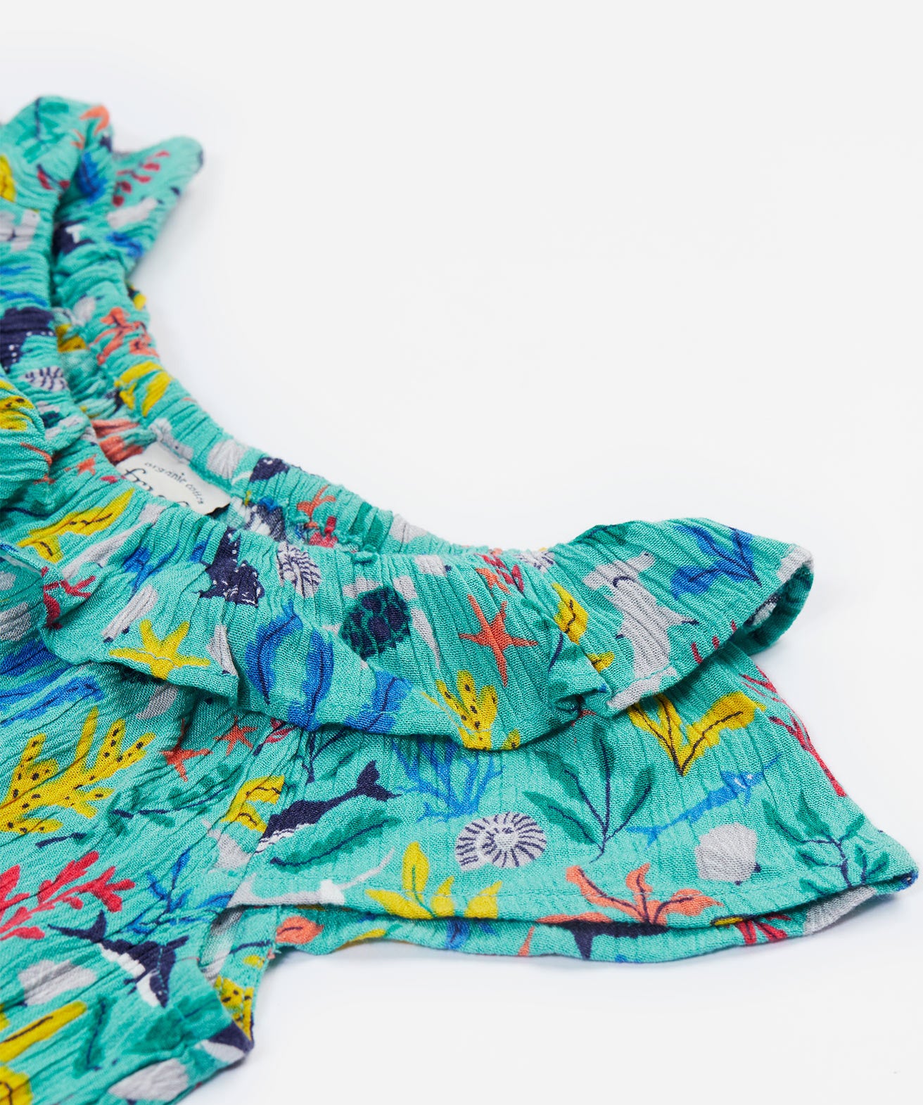 A close up of the Frugi Maris Playsuit, featuring a Sea Life print's frilly collar.