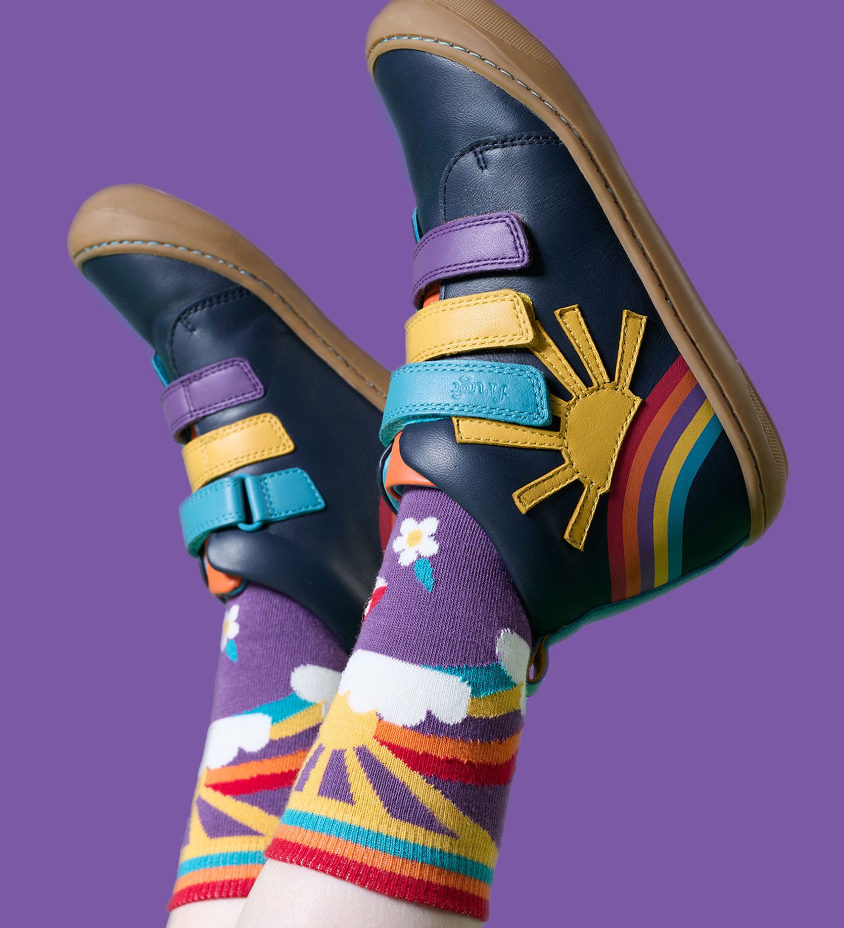 A child wearing the Frugi meadow high top children's shoes with matching purple coloured rainbow, sun flower design Frugi socks. 