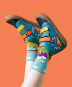 A child wearing the Frugi meadow high top leather children's shoes with a keep it wild design on a boat blue colour with Frugi mountain themed organic cotton socks.