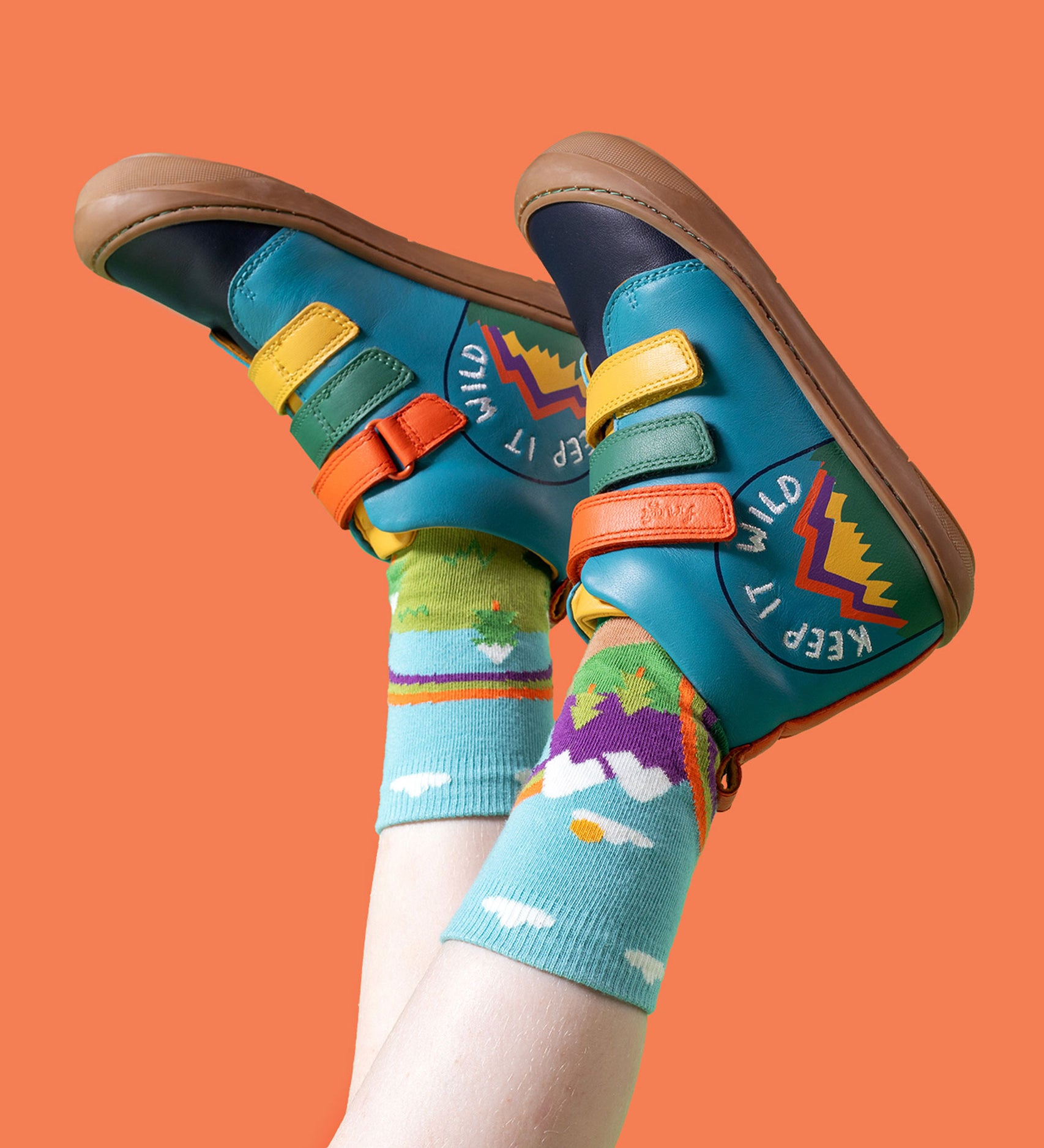 A child wearing the Frugi meadow high top leather children's shoes with a keep it wild design on a boat blue colour with Frugi mountain themed organic cotton socks.