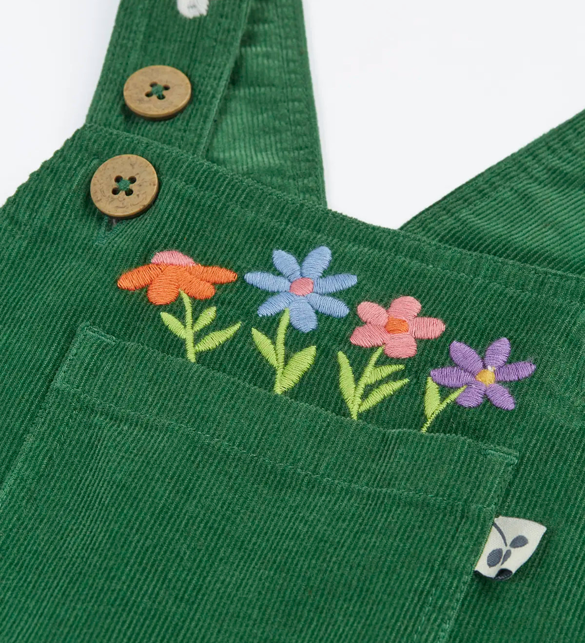 Close up of the embroidered flowers above the pocket on the front of the Frugi Miley holly green cord dungaree.