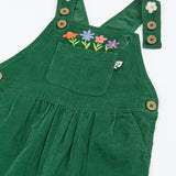 Close up of the front of the Frugi Miley holly green cord dungaree with flowers embroidery details, shown with one strap open.