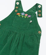 Close up of the front of the Frugi Miley holly green cord dungaree with flowers embroidery details, shown with one strap open.