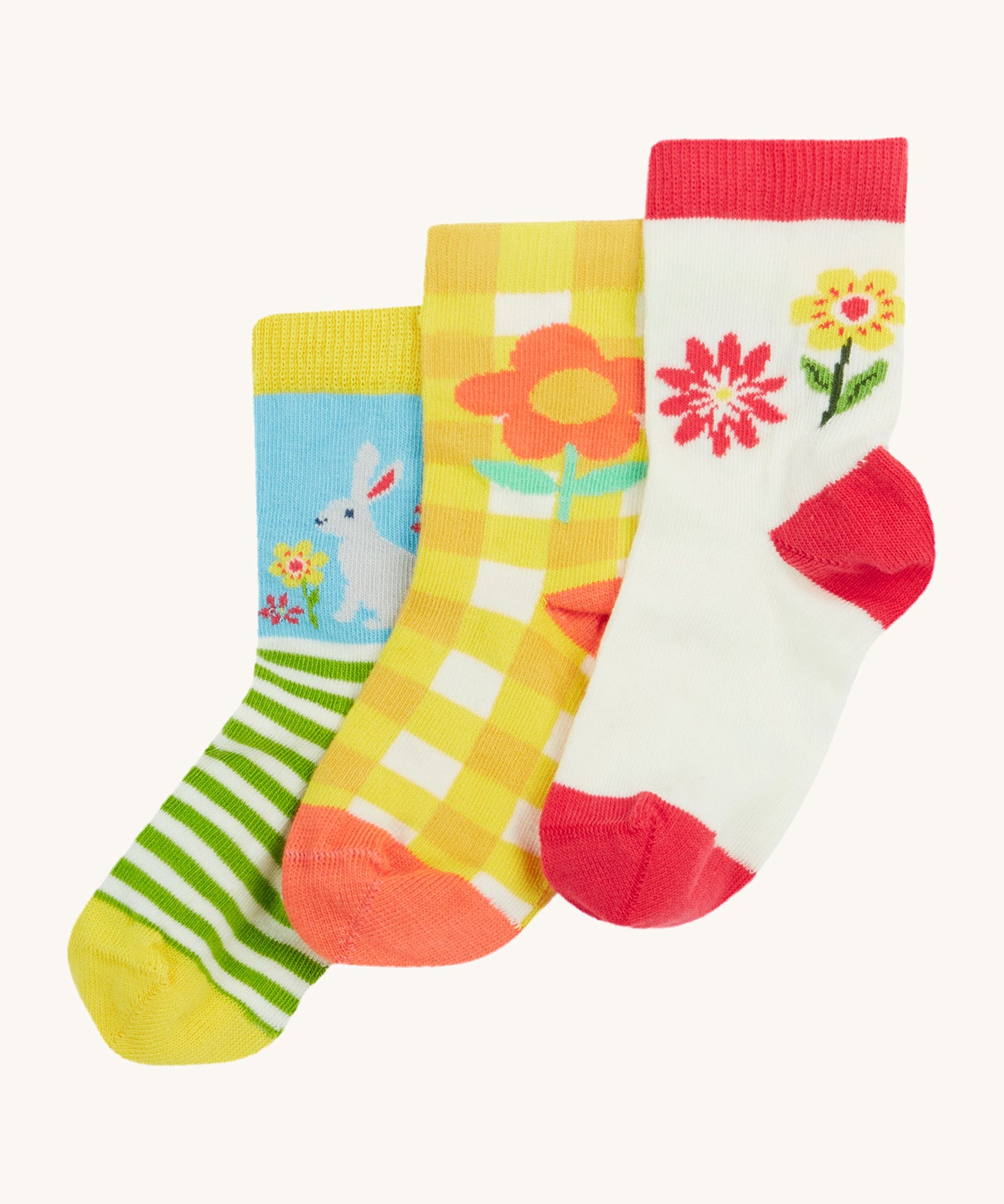 Frugi kids spring 3 pack socks - GOTS organic kids socks which features a white sock with a pink trim and flowers. A yellow gingham sock with a flower design and a green striped sock with a rabbit design.