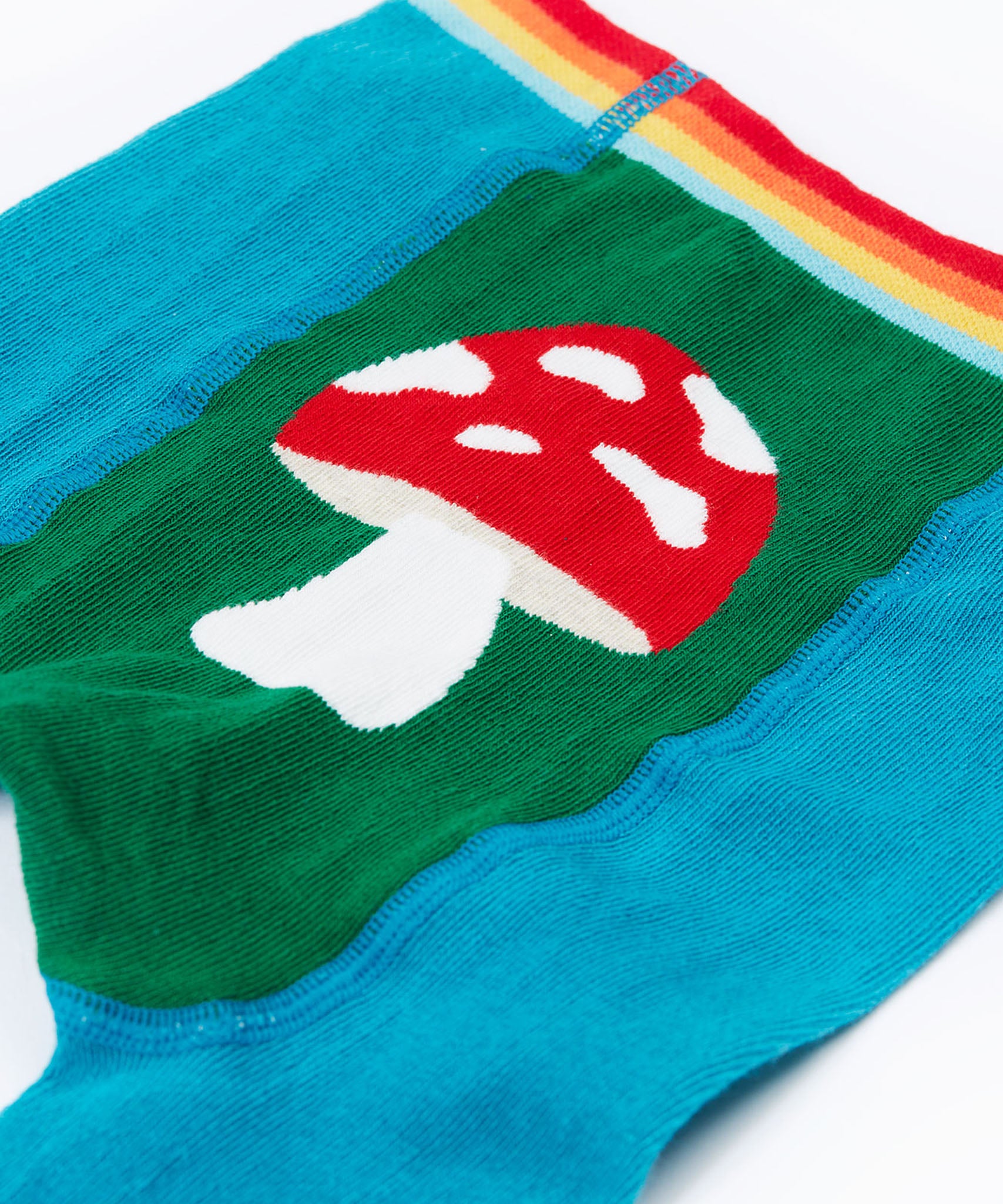 A close up of the red mushroom on the back of the Frugi organic cotton little knitted leggings with a fun guys red mushroom and farm design.