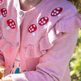 A close up of the mushrrom details on the Frugi pink marl Romi cardigan. A child is wearing the organic cotton cardigan.