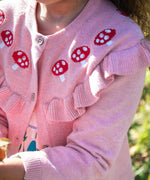 A close up of the mushrrom details on the Frugi pink marl Romi cardigan. A child is wearing the organic cotton cardigan.