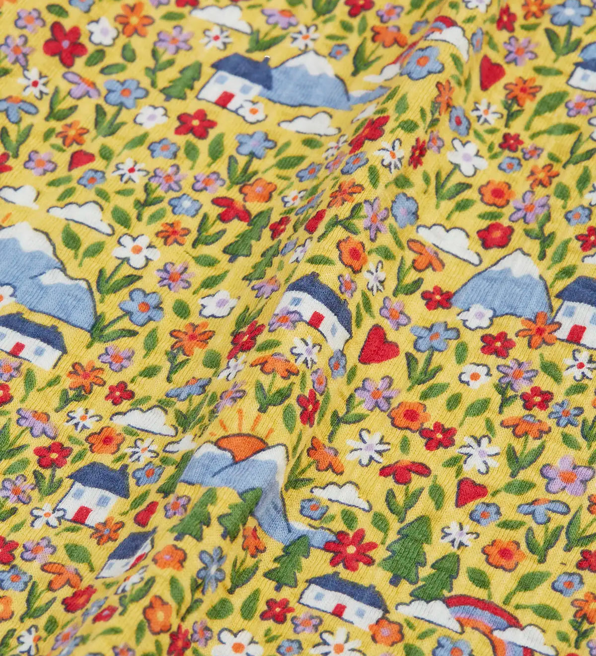 Close up of the highland houses themed print on the Frugi Natasha long sleeve organic cotton top in yellow. The print features flowers, mountains and a simple white house.