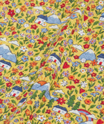 Close up of the highland houses themed print on the Frugi Natasha long sleeve organic cotton top in yellow. The print features flowers, mountains and a simple white house.