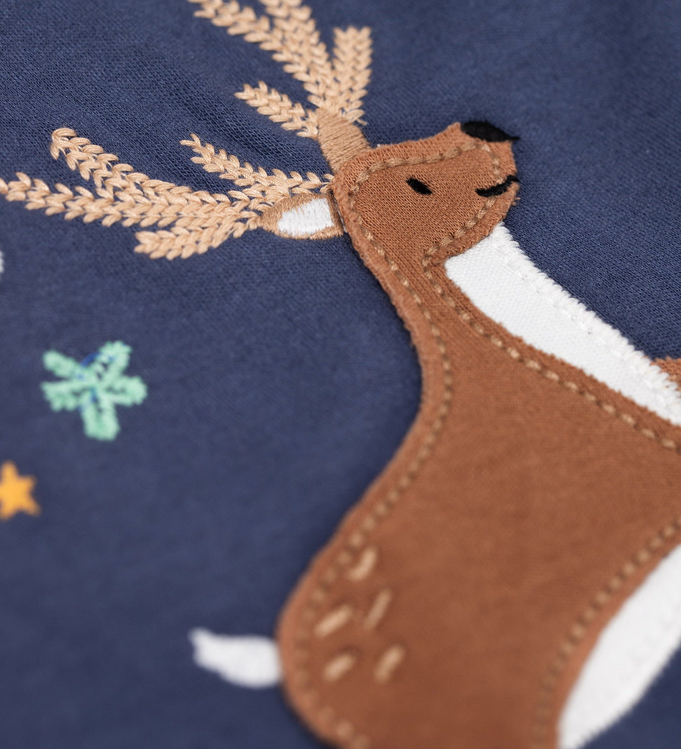 A close up of the reindeer applique on the front of the Frugi Navy Organic Cotton Caris Reindeer Applique Top. This top is a part of a wide range of organic cotton clothing for children available here at Babipur. 