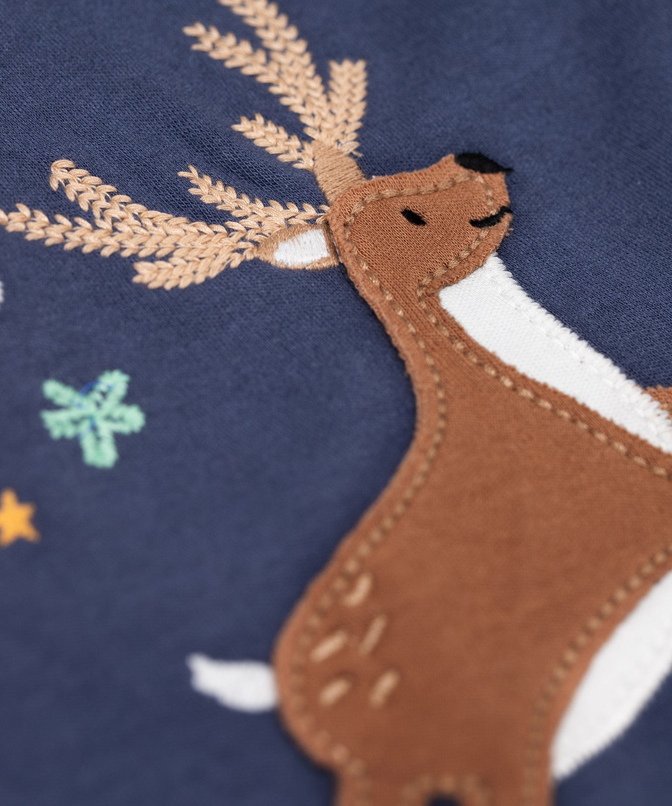 A close up of the reindeer applique on the front of the Frugi Navy Organic Cotton Caris Reindeer Applique Top. This top is a part of a wide range of organic cotton clothing for children available here at Babipur. 