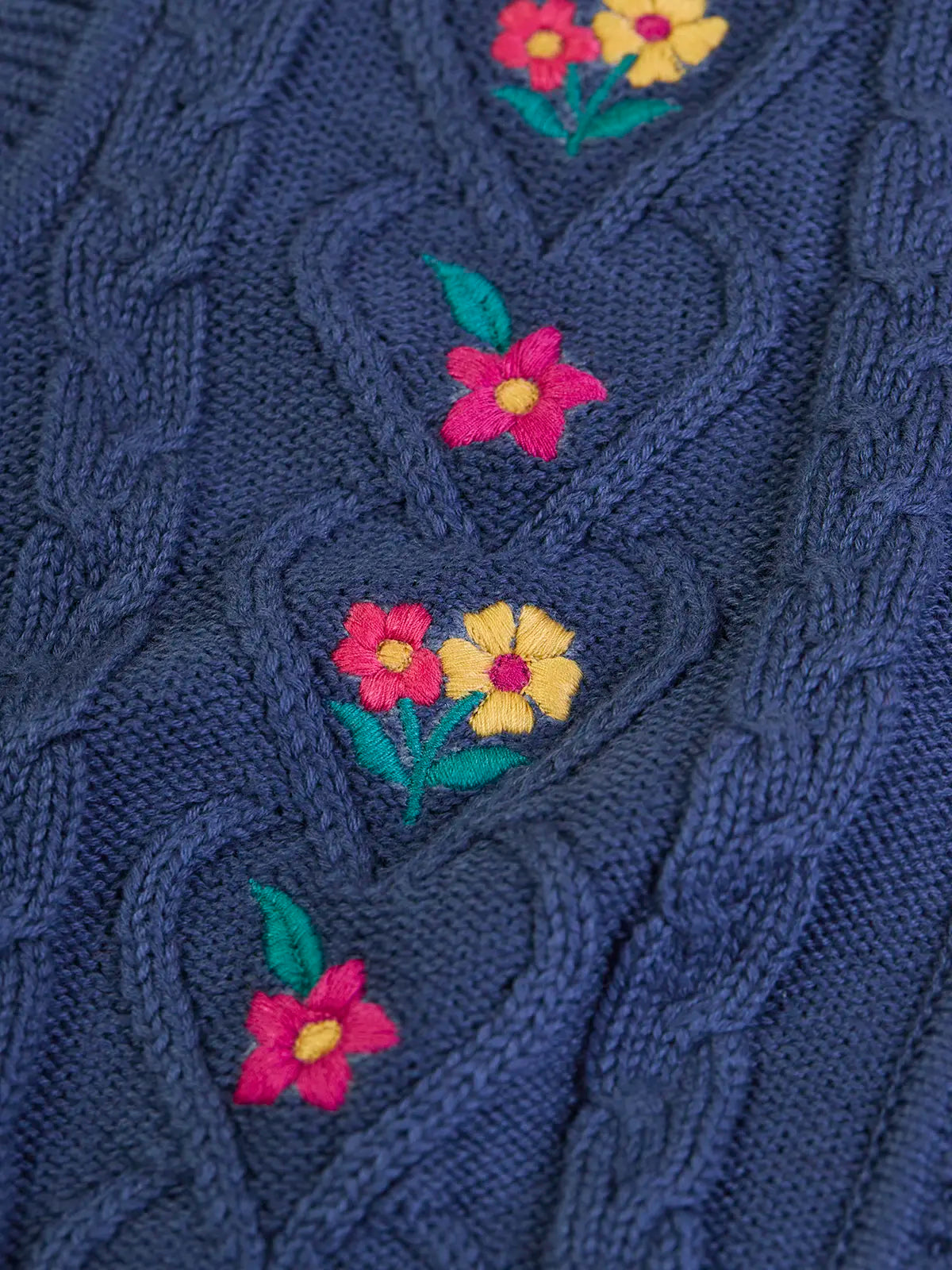 Close up of the embroidered pink and yellow flowers on the front of the Frugi organic cotton connie knitted waistcoat.