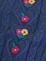 Close up of the embroidered pink and yellow flowers on the front of the Frugi organic cotton connie knitted waistcoat.