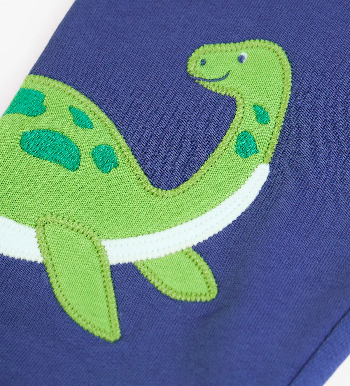 Close up of the green loch ness monster applique on the Frugi navy nessie organic cotton kids character joggers.