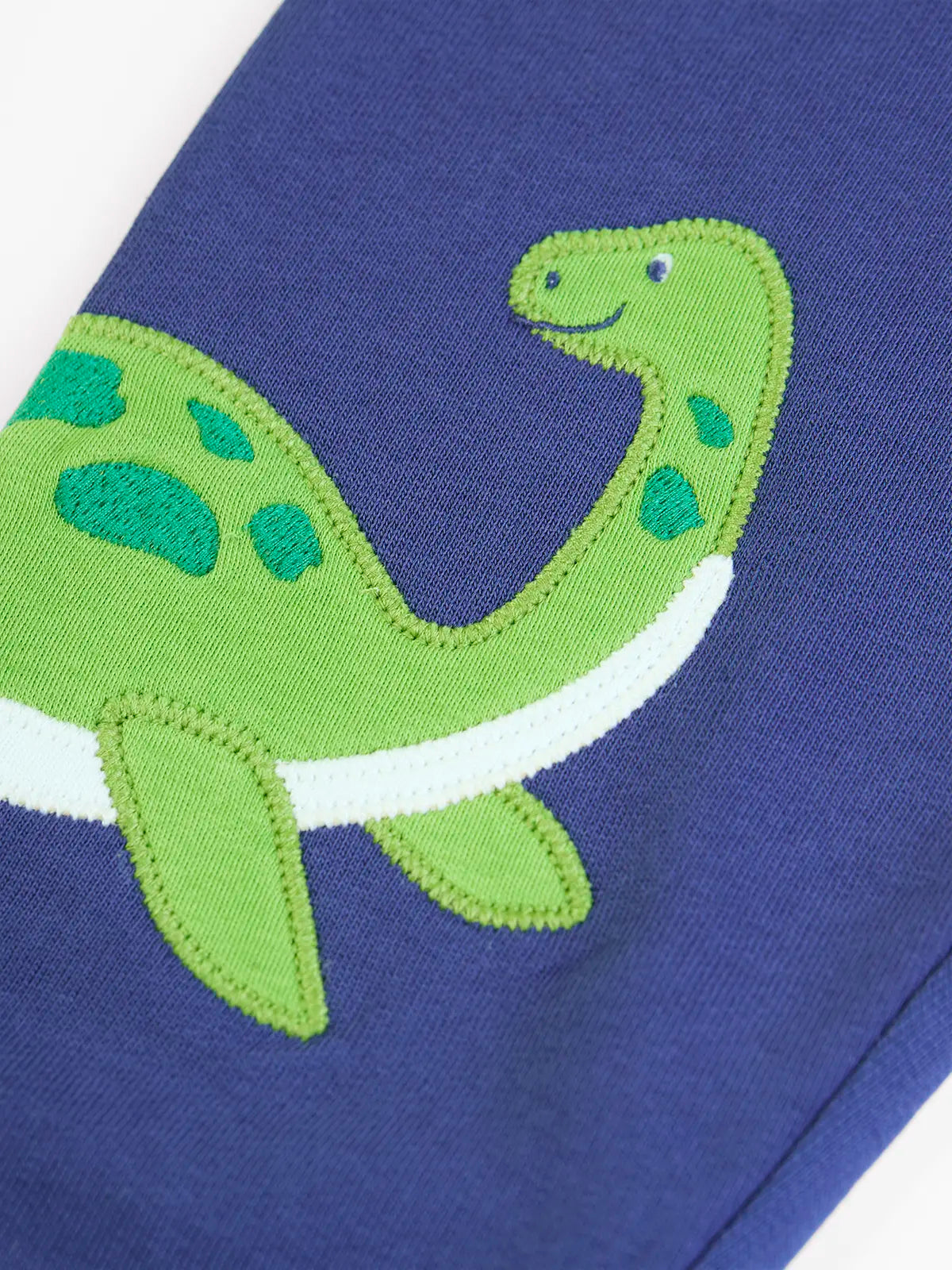 Close up of the green loch ness monster applique on the Frugi navy nessie organic cotton kids character joggers.