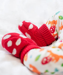 A close up of a baby wearing the Frugi kids noa knitted booties in red mushroom showing the knit detail. 