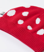 A close up of the Frugi kids noa knitted hat in red mushroom showing the ribbed brim detail on red organic cotton fabric