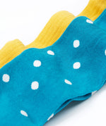 A close up of the blue coloured mushroom design tights from the Frugi Norah 2 pack tights. These child's footed tights have a turquoise blue background with white dots. The bumblebee yellow coloured tights can be seen in the background.