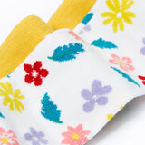 A close up of the print details on the Frugi flowers design tights from the Norah tights 2 pack. A white background with different coloured flowers and blue green coloured leaves all over the legs. 