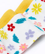 A close up of the print details on the Frugi flowers design tights from the Norah tights 2 pack. A white background with different coloured flowers and blue green coloured leaves all over the legs. 