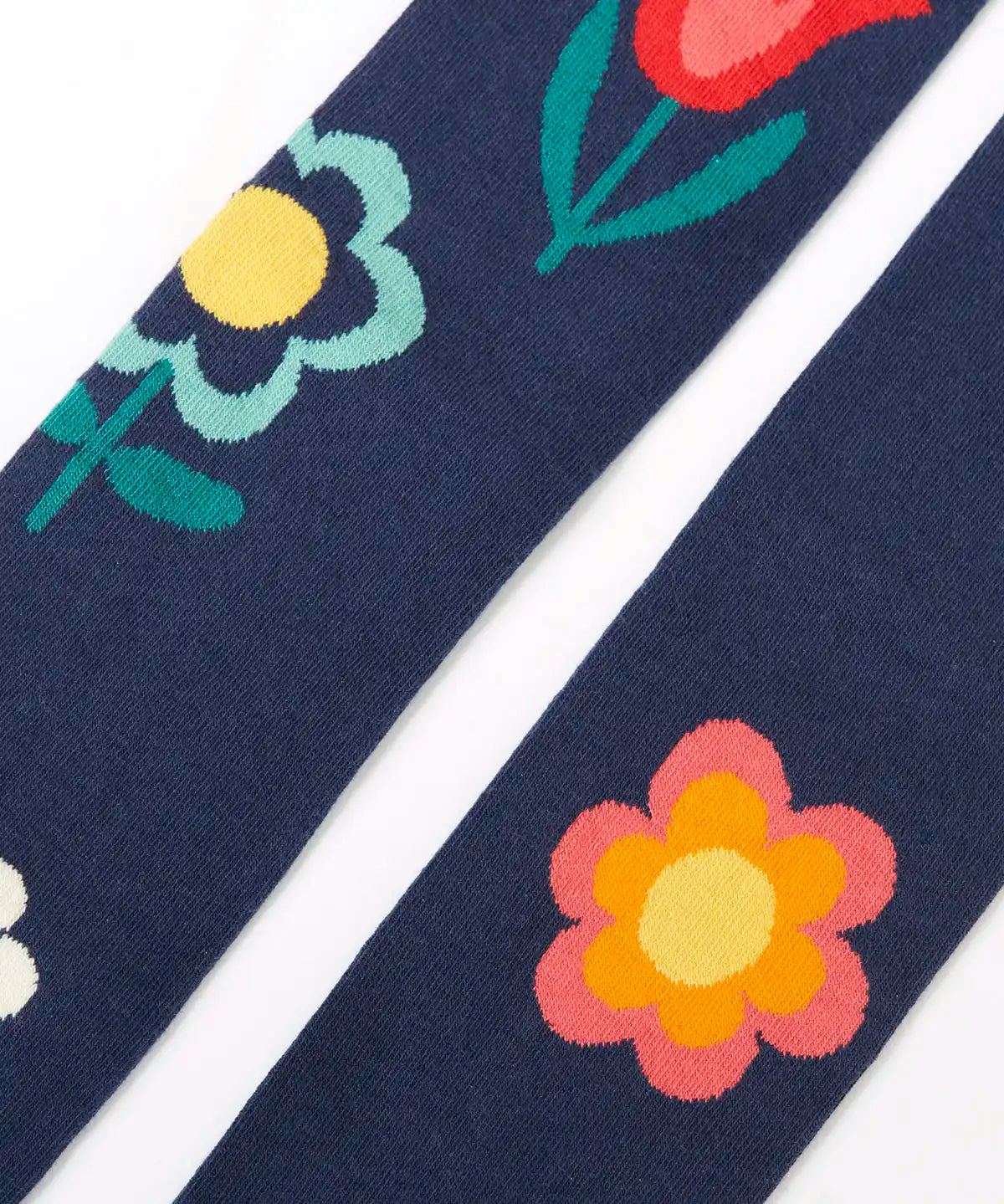 Close up of the Frugi children's Norah organic cotton knitted tights in navy blue with flowers.