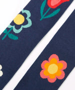 Close up of the Frugi children's Norah organic cotton knitted tights in navy blue with flowers.
