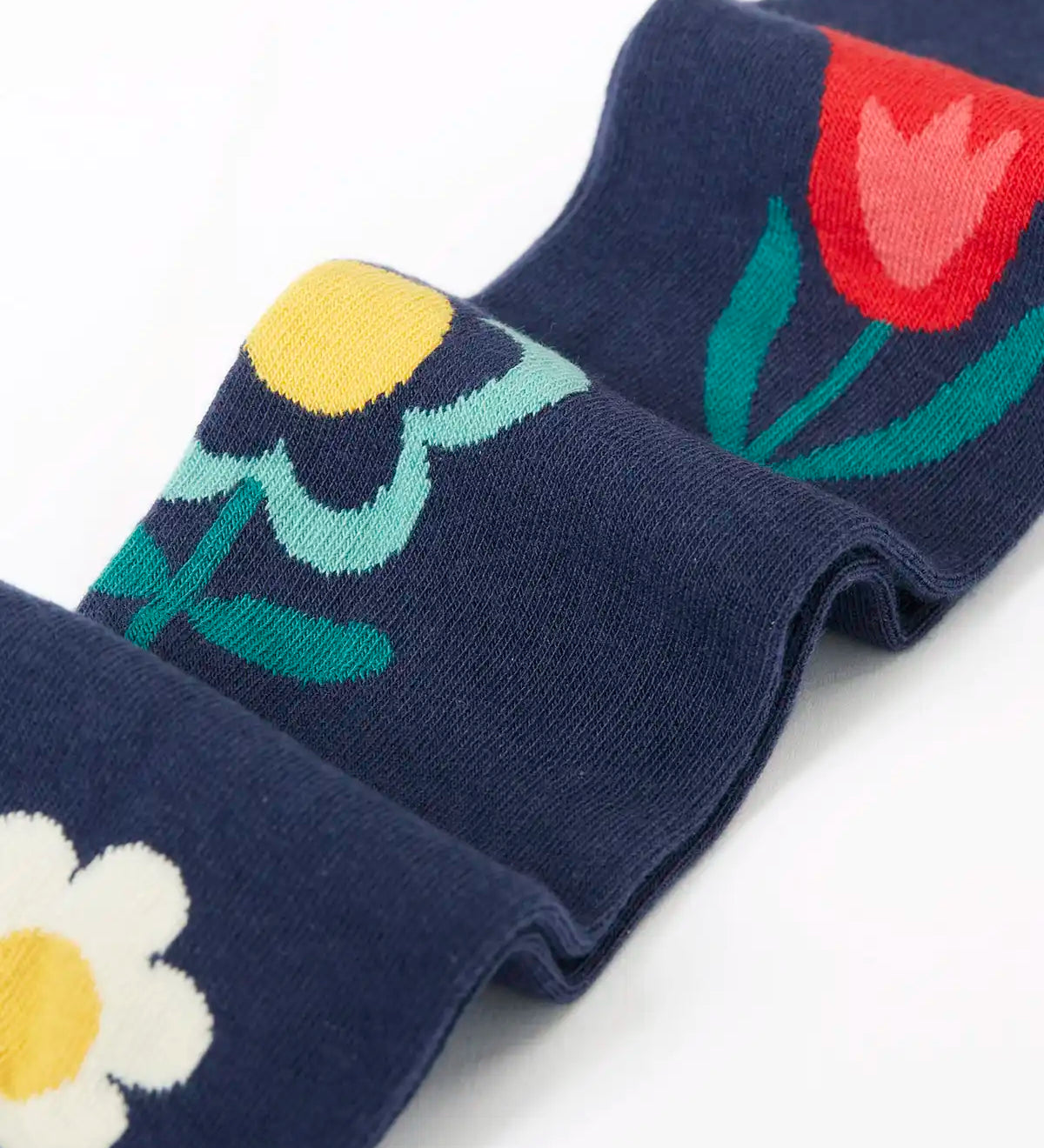 Close up of the Frugi children's Norah organic cotton knitted tights in navy blue with flowers.