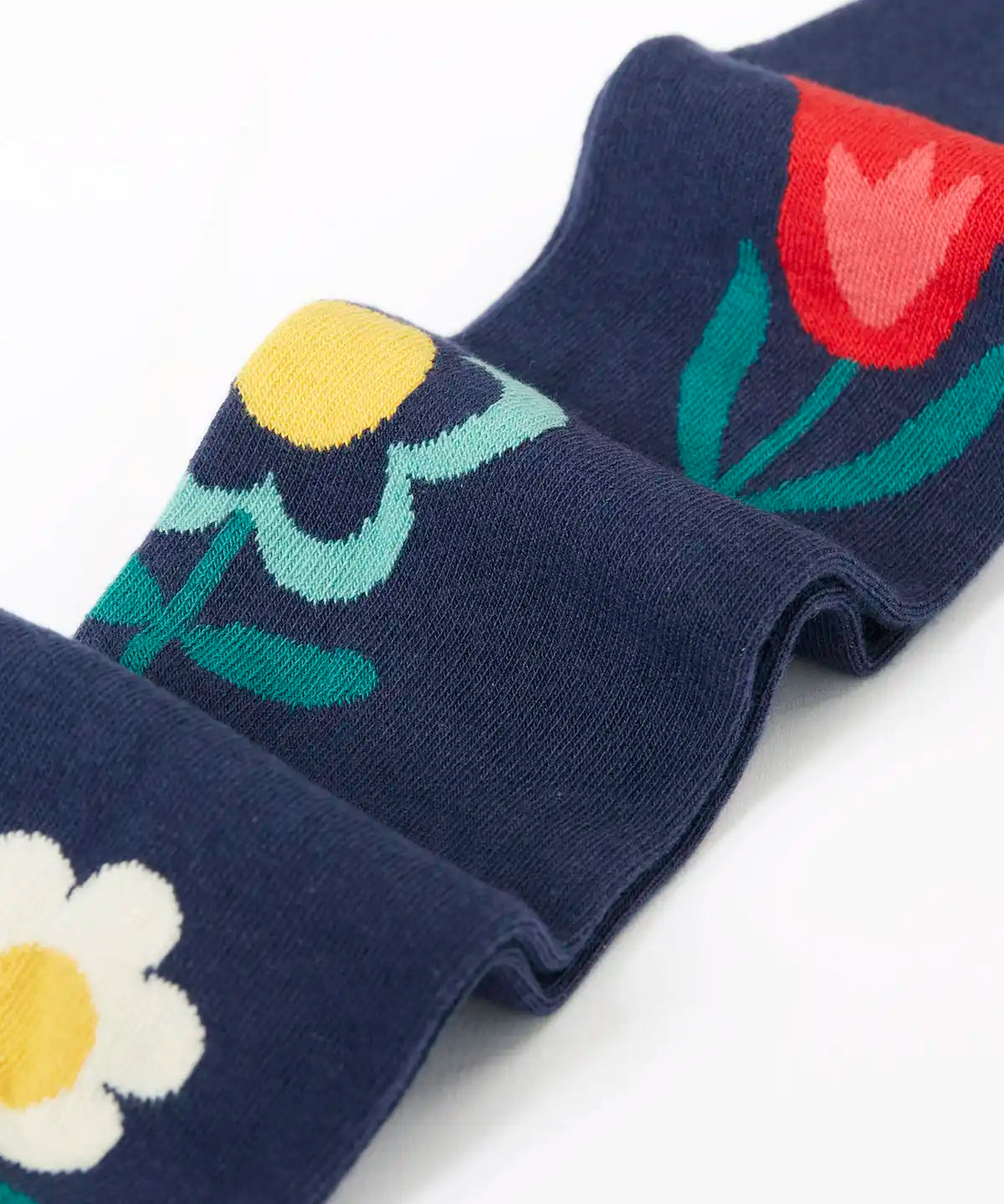 Close up of the Frugi children's Norah organic cotton knitted tights in navy blue with flowers.