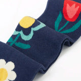 Close up of the Frugi children's Norah organic cotton knitted tights in navy blue with flowers.