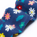 A close up of the legs on the Frugi Norah footed navy flowers tights. The flowers design features  different coloured flowers and blue leaves all print on a navy background.

