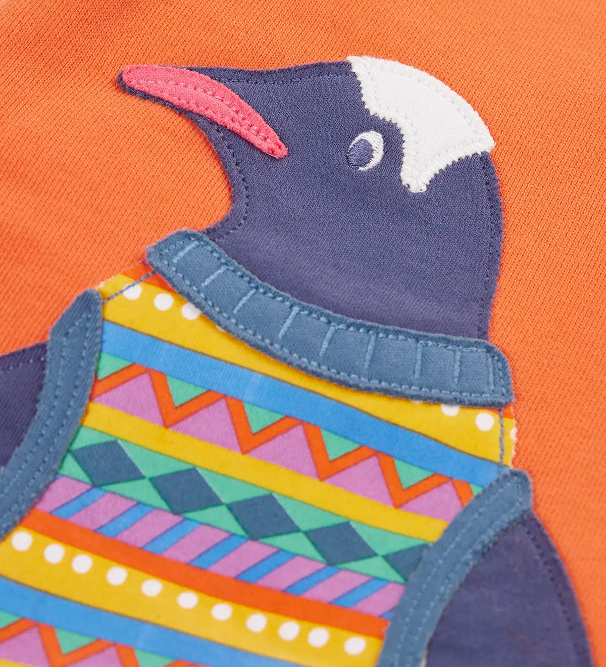 Close up of the penguin applique on the salamander orange Frugi organic cotton superb sweatshirt .
