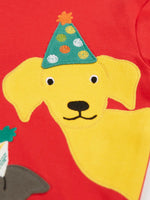 Close up of the yellow Labrador dog wearing a green party hat applique on the Frugi organic cotton adventure circular long sleeve top .