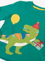 Close up of the green t-rex dinosaur wearing a red party hat applique on the Frugi organic cotton adventure long sleeve hut green child's top.