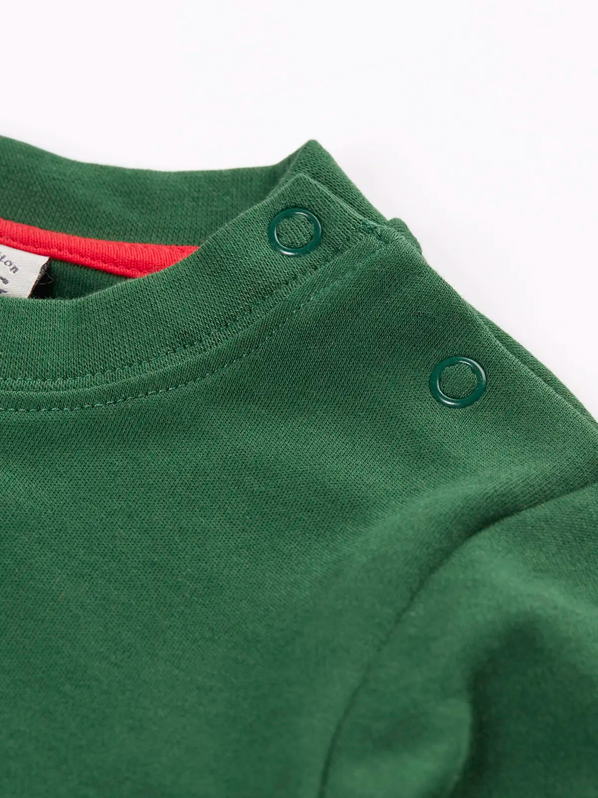 Close up of popper closure on teh shoulders of the Frugi organic cotton adventure long sleeve top in forest green with large fox applique on the front.
