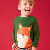 Child wearing the Frugi organic cotton adventure long sleeve top in forest green with large fox applique on the front with festive check trousers.