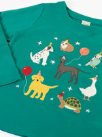 Close up of the Frugi organic cotton anna pet Paw-Ty appliqué long sleeve children's top. Green top with applique dogs, guinea pig, budgie, goose and tortoise wearing party hats and balloons and star sparkle details. 