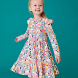 Child wearing the Frugi organic cotton annika skater dress with floral flight print and frilled shoulders. All over print featuring pegasus, flowers and foliage. 