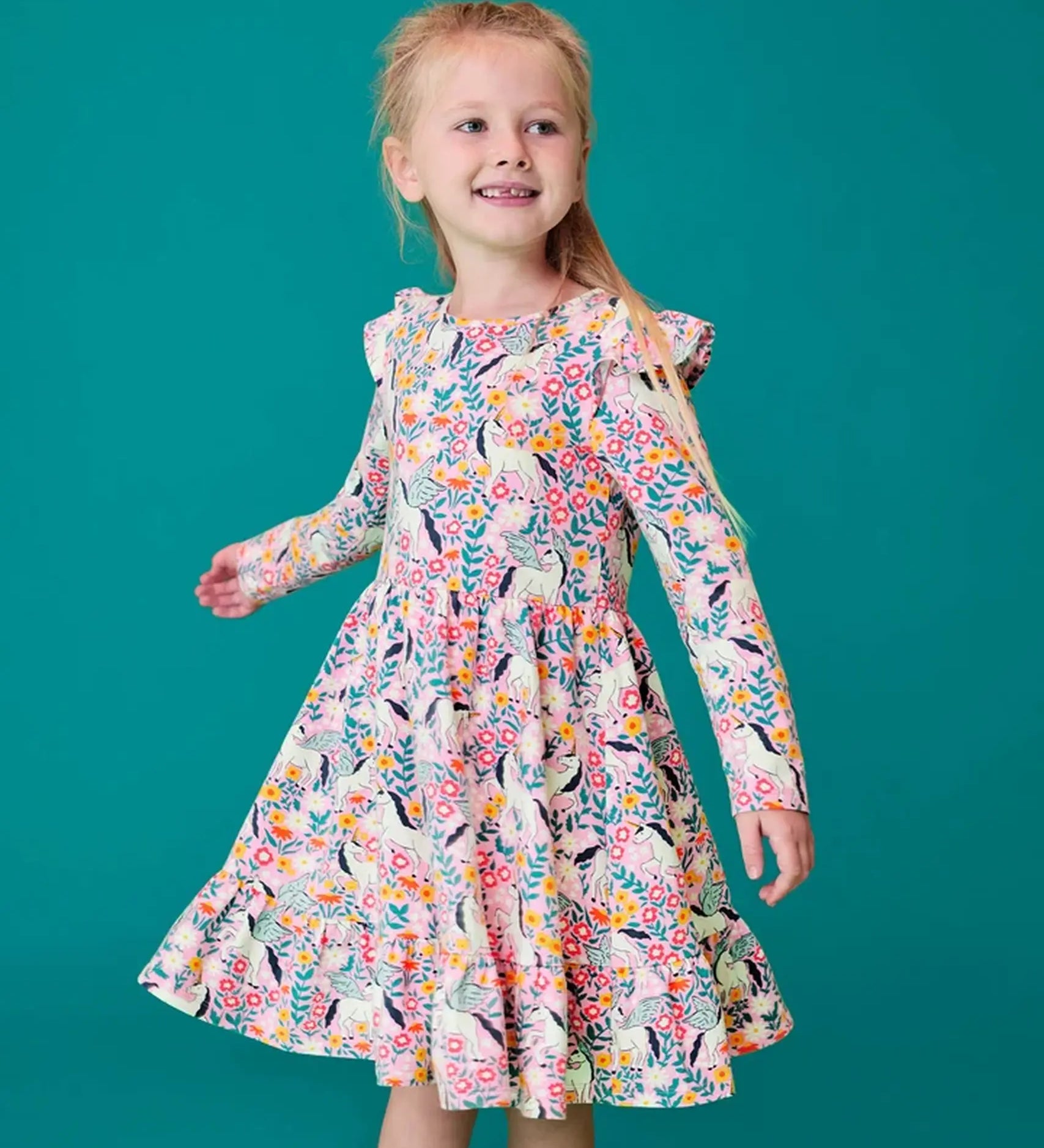 Child wearing the Frugi organic cotton annika skater dress with floral flight print and frilled shoulders. All over print featuring pegasus, flowers and foliage. 