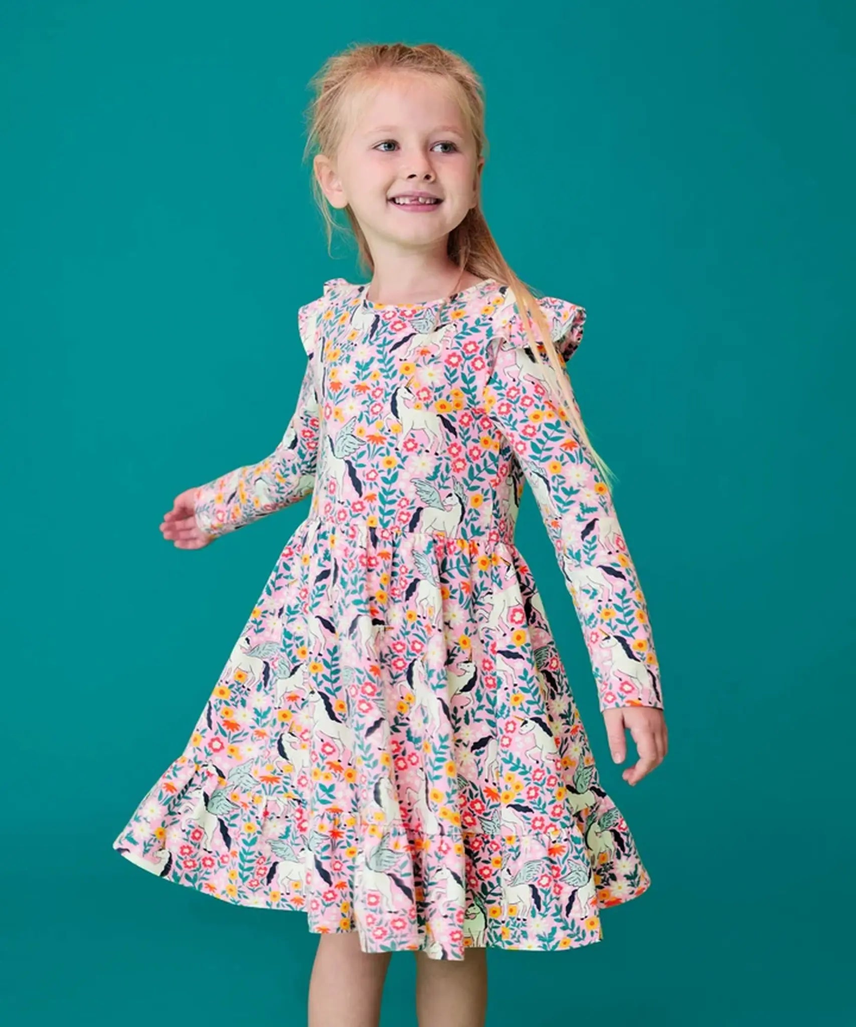 Child wearing the Frugi organic cotton annika skater dress with floral flight print and frilled shoulders. All over print featuring pegasus, flowers and foliage. 