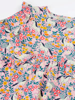 Close up of the front of the Frugi organic cotton annika skater dress with floral flight print showing the filled shoulders.