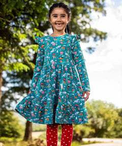 Child wearing the Frugi organic cotton annika skater dress with winter drives print. All over print featuring houses, campers, snow topped mountains, snowman and trees in a festive scene. 
