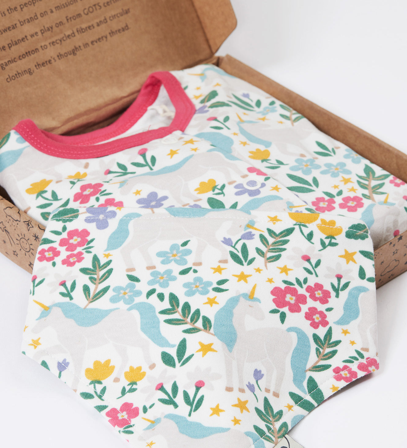 A close up of the bandanna style bib included in the Frugi Unicorn Forest Organic Cotton Babygrow Gift Set. This baby grow set  comes with a white babygrow decorated with an all over unicorn forest themed print and comes with a matching bandanna style bib. 
This baby gift set is a part of a wide range of organic cotton clothing for children available here at Babipur. 