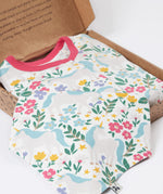 A close up of the bandanna style bib included in the Frugi Unicorn Forest Organic Cotton Babygrow Gift Set. This baby grow set  comes with a white babygrow decorated with an all over unicorn forest themed print and comes with a matching bandanna style bib. 
This baby gift set is a part of a wide range of organic cotton clothing for children available here at Babipur. 